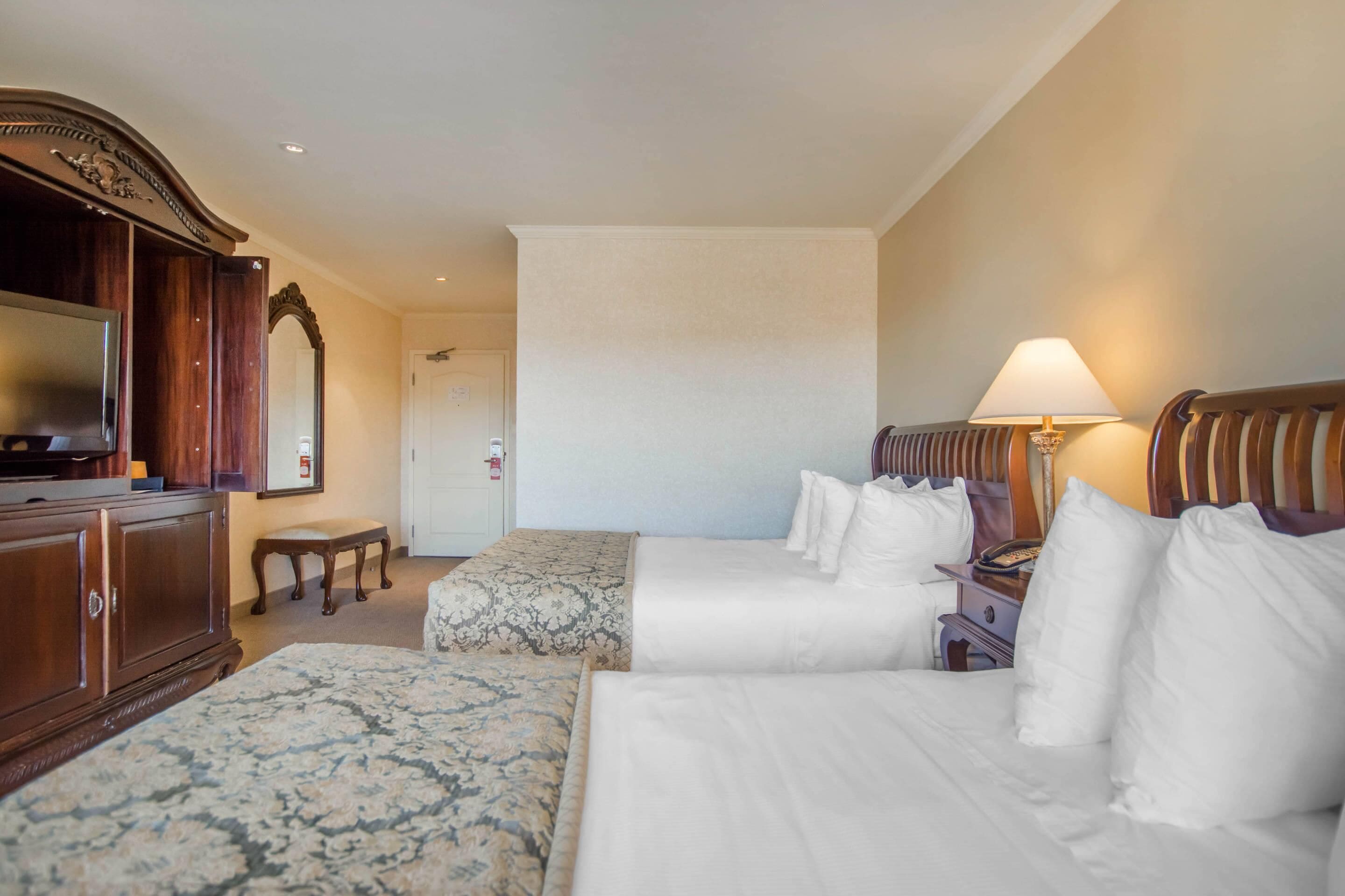 Habitación de hotel con dos camas, televisión, escritorio y lámpara.