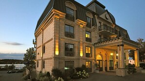 A large, multi-story hotel with a grand entrance, large windows, and a well-lit facade. - St Christophe Hotel & Spa, an Ascend Collection Hotel (Granby)