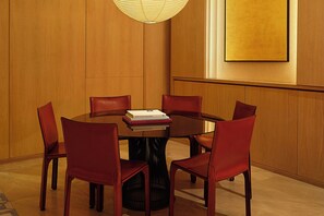 A conference room with a round table, six chairs, and a stack of books on the table. - GEM Hotel - Chelsea (New York)