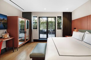 A hotel room with a bed, a desk, a bench, a wardrobe, and a view of the outside. - GEM Hotel - Chelsea (New York)