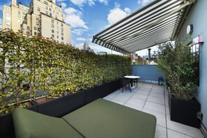 A rooftop patio with a green sofa, a small table, and chairs. - GEM Hotel - Chelsea (New York)