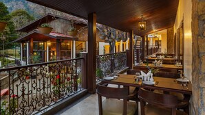 Un restaurant doté d’une terrasse, de tables et de chaises en bois, offrant une vue sur un paysage montagneux.