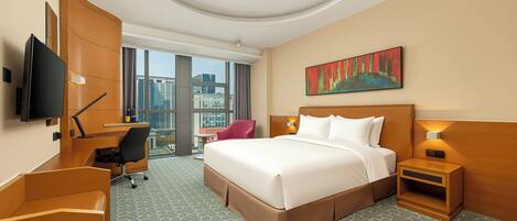 A hotel room with a large bed, a desk, a chair, a TV, a nightstand, and a painting.