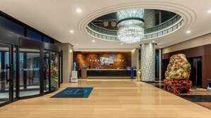 A hotel lobby with a reception desk, a chandelier, a glass elevator, and a unique sculpture. - Holiday Inn Express Beijing Wangjing Center by IHG  (Beijing)