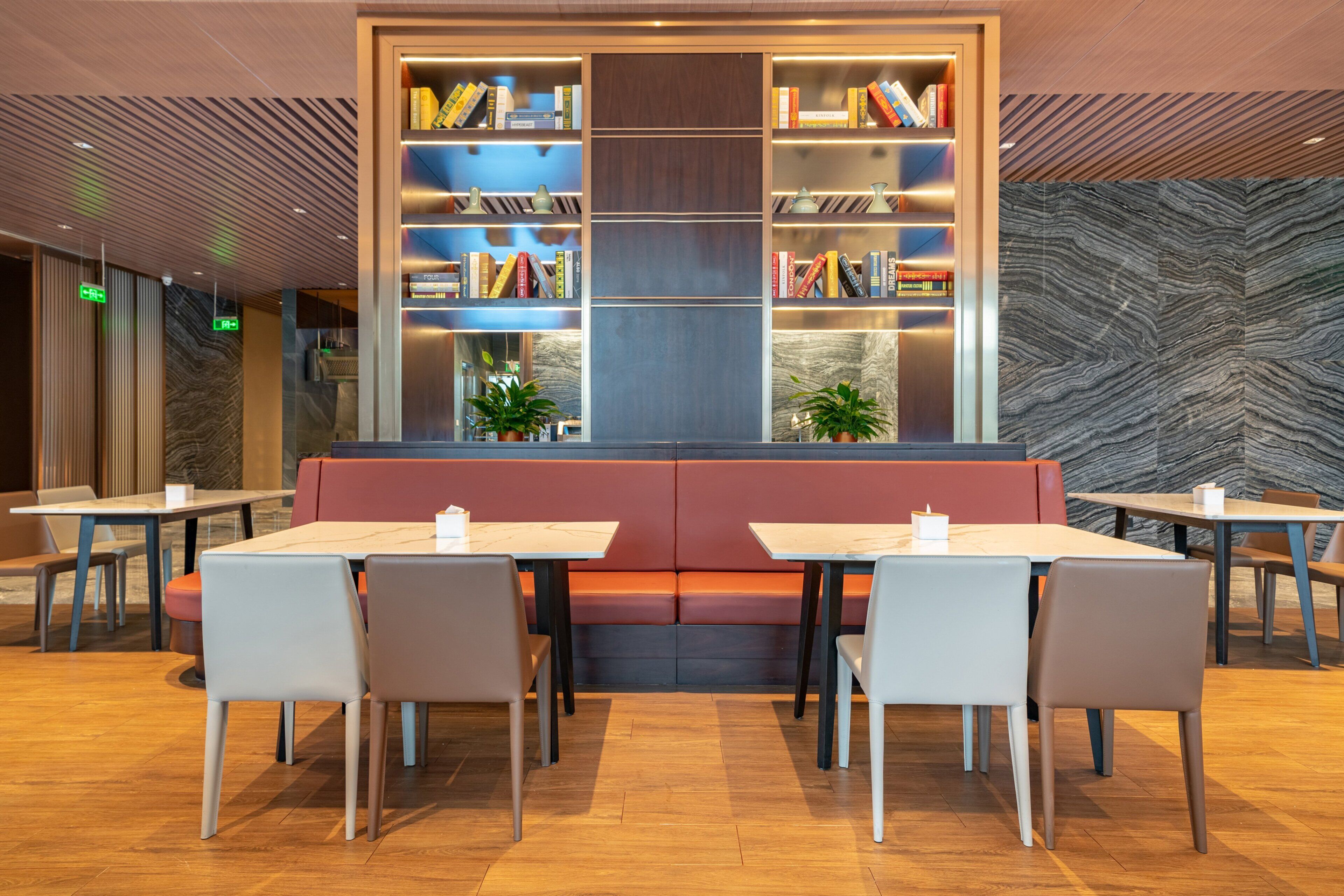 Un'area pranzo moderna con una zona salotto centrale, diversi tavoli e scaffali.