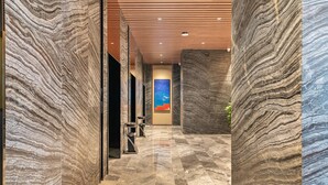 A hallway with marble walls and a tiled floor, leading to a reception area with a painting of a bird in flight. - Holiday Inn Express Beijing Wangjing Center by IHG  (Beijing)