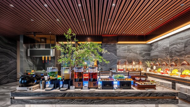 A modern hotel lobby with a marble reception desk, a large plant, and a variety of amenities including a coffee station and a buffet. - Holiday Inn Express Beijing Wangjing Center by IHG  (Beijing)
