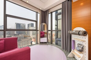 A modern hotel room with large windows, a bed, a mirror, a yoga mat, and a wall-mounted shelf with a kettlebell. - Holiday Inn Express Beijing Wangjing Center by IHG  (Beijing)