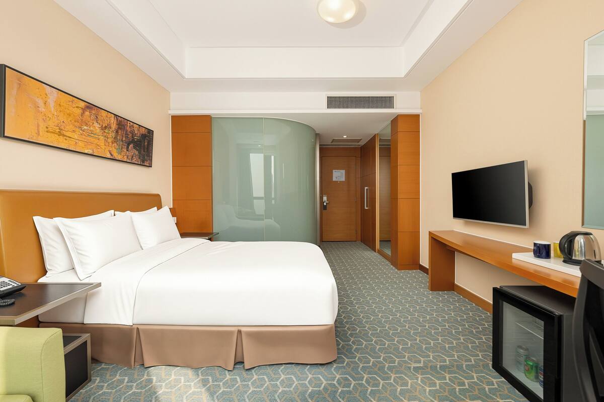 A hotel room with a bed, a television, a desk, and a coffee maker.
