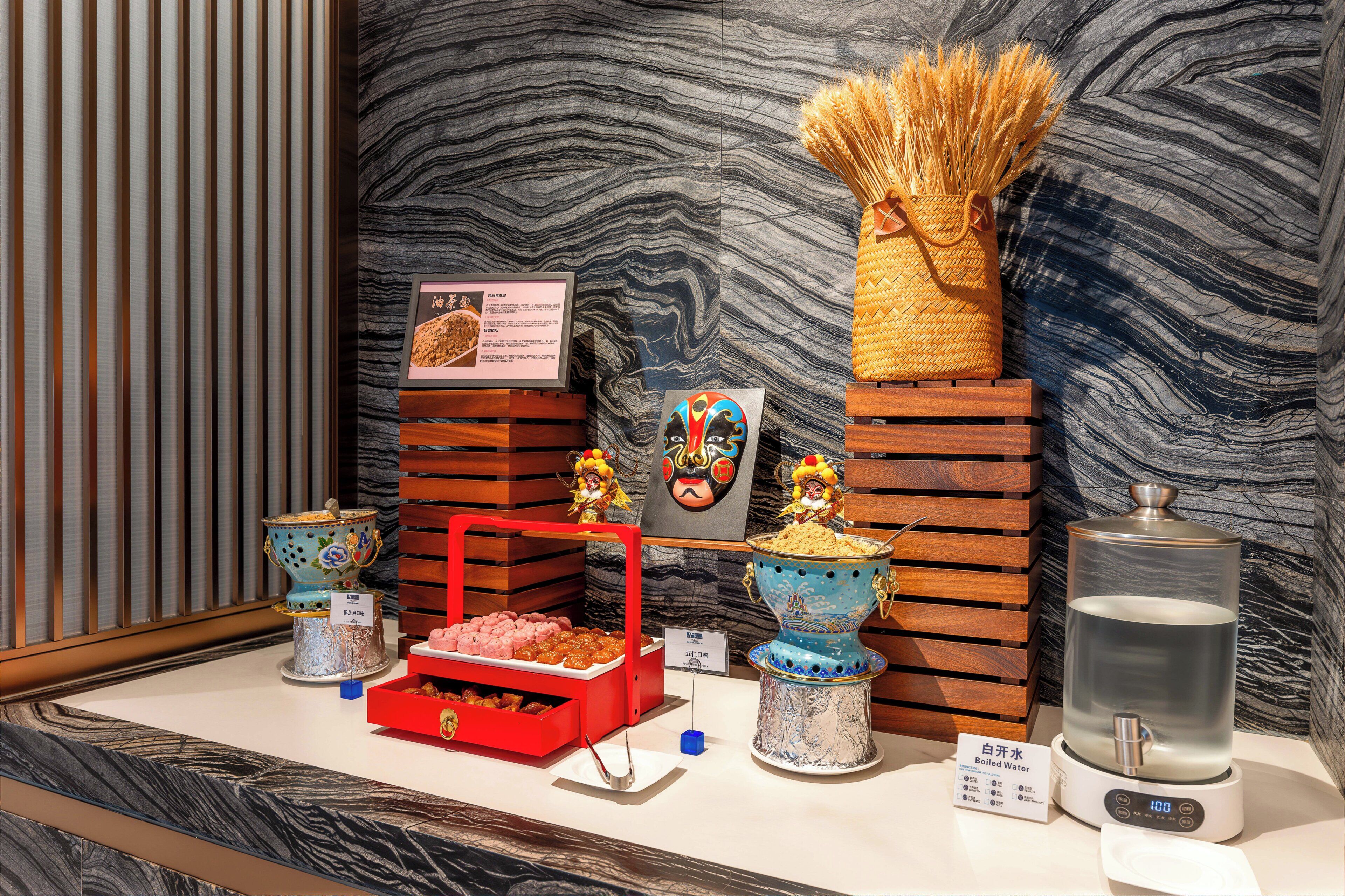 Une exposition de jeux de thé traditionnels chinois, d’un distributeur d’eau et d’objets décoratifs, le tout mis en valeur sur un mur de marbre.