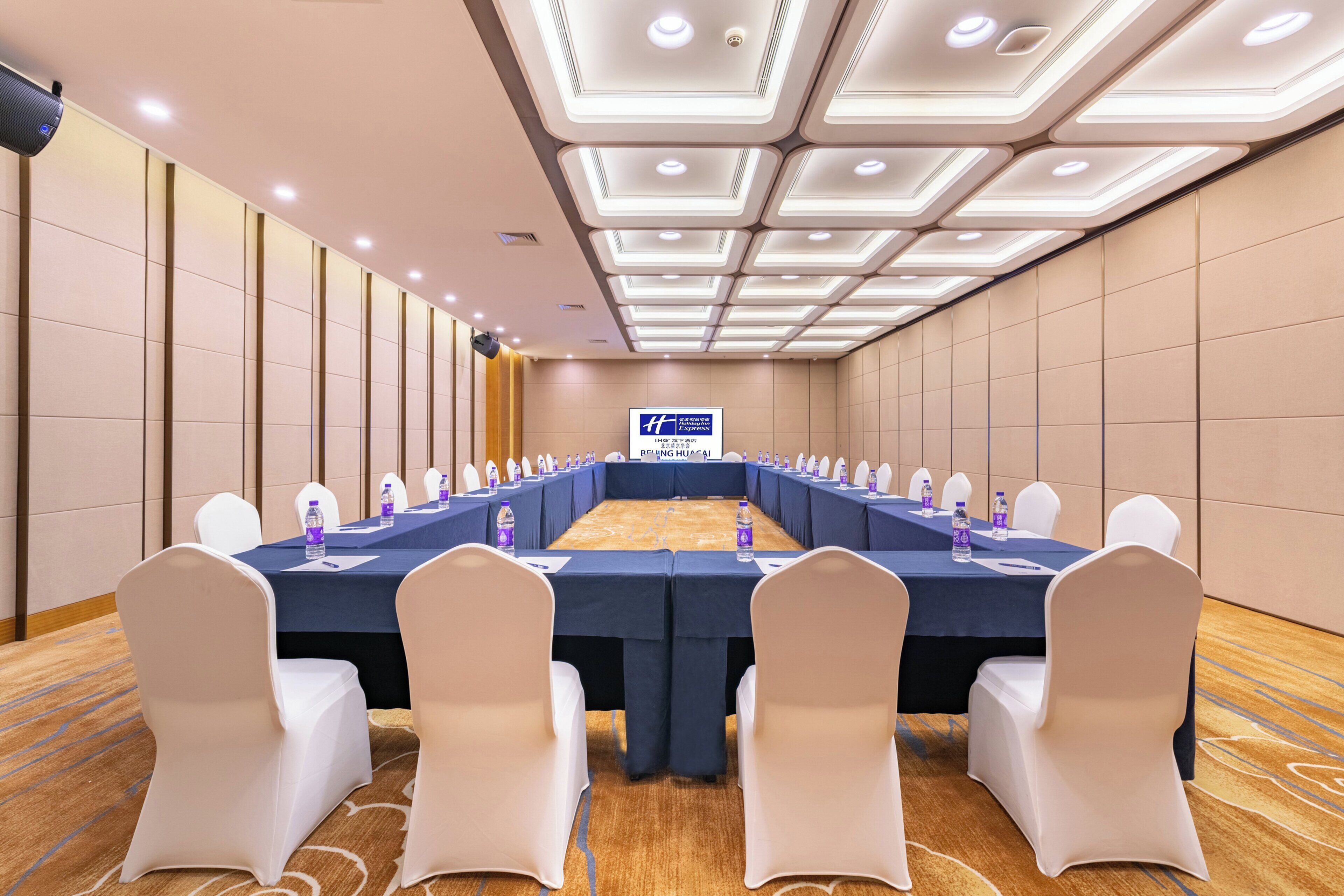 A conference room with a long table, white chairs, and a sign indicating it's a Holiday Inn Express location.