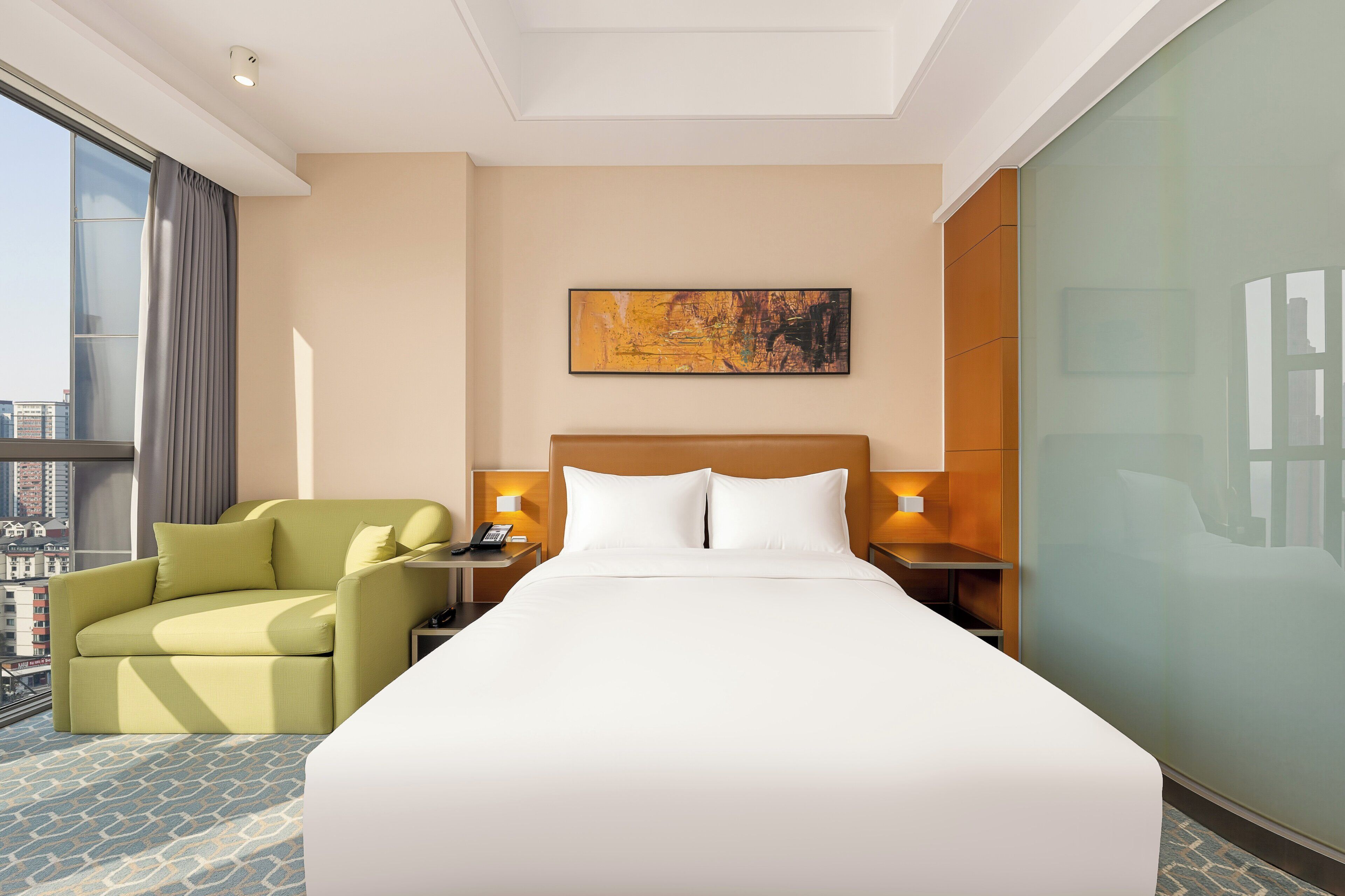 Een hotelkamer met een groot bed, een bank, een schilderij aan de muur en uitzicht op de stad.