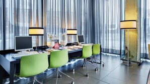 Een moderne kantoorruimte met een lange tafel, meerdere stoelen, twee computers en twee lampen.