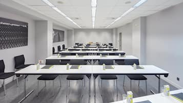 A conference room with multiple tables, chairs, and water bottles.