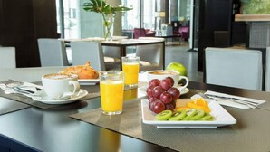 Een ontbijtsetting met croissants, fruit, sap en een kop koffie op een tafel.