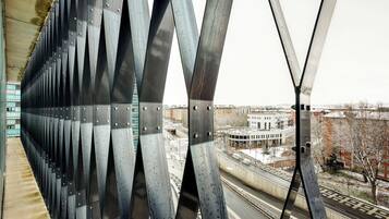 Blick auf eine Brücke mit einer Reihe von dreieckigen Metallstützen und einer Stadtkulisse im Hintergrund.