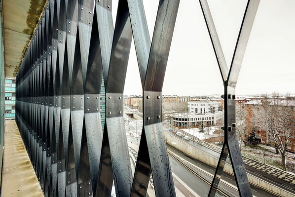 A view of a bridge with a series of triangular metal supports and a cityscape in the background.