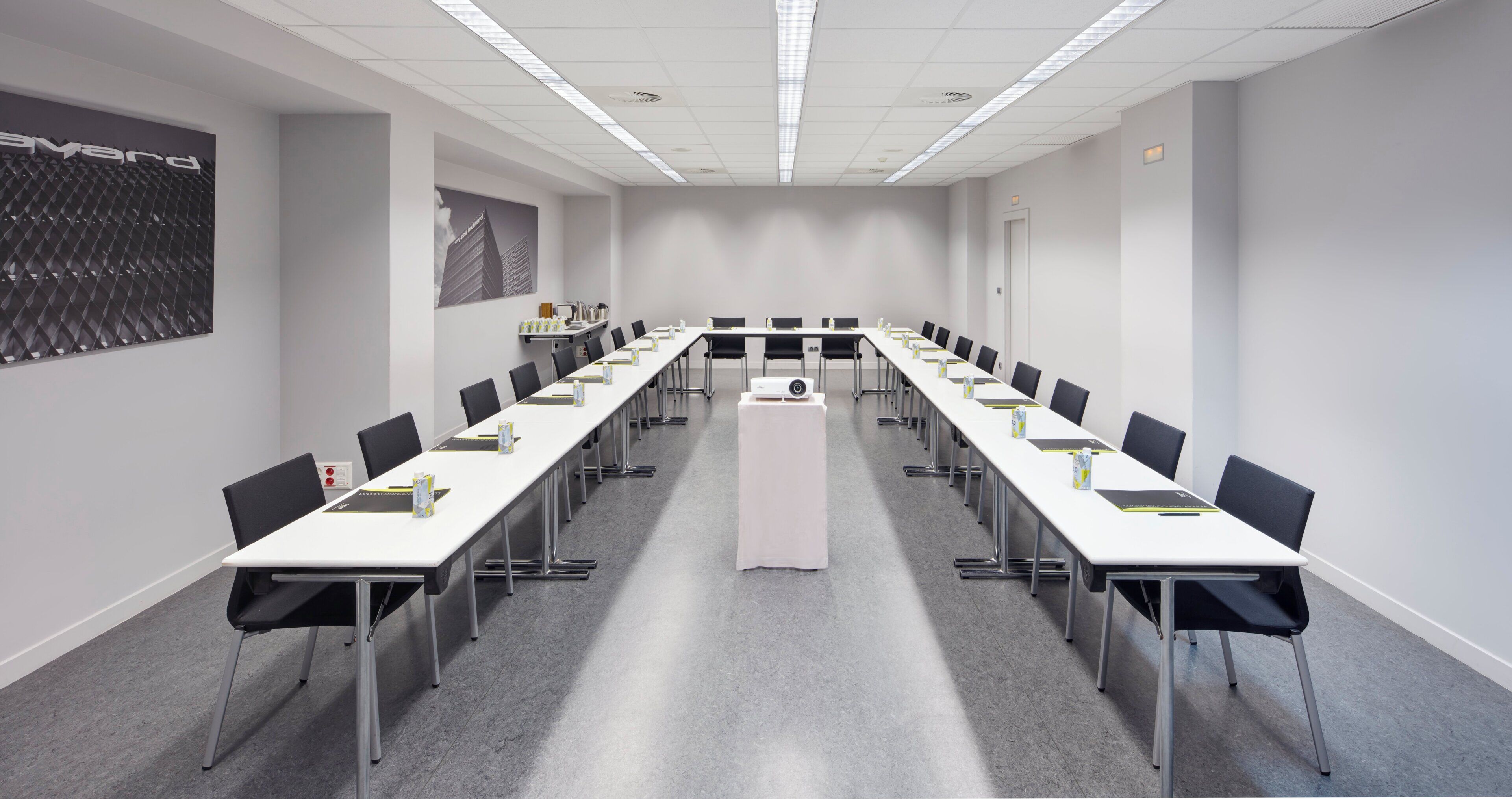 Een congrescentrum met lange tafels, stoelen en een beamer.