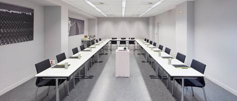 A conference room with long tables, chairs, and a projector.