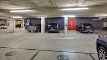A parking garage with multiple parking spaces, a fire extinguisher, and a hotel sign.