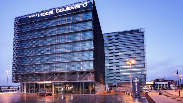 Een modern hotel met een opvallend 'Hotel Boulevard' bord, met een unieke geometrische gevel en een glazen ingang.
