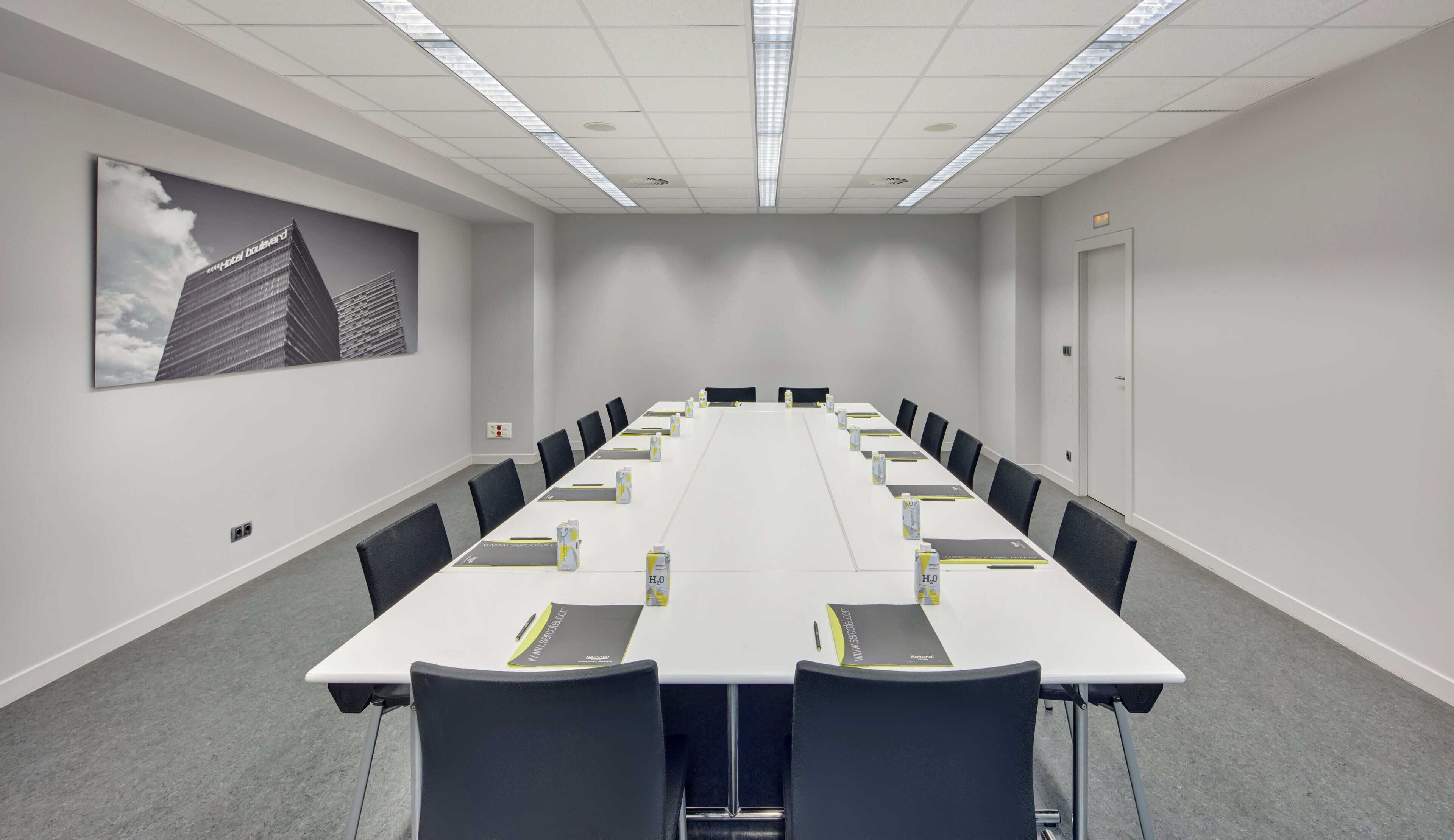 A conference room with a long table, chairs, and a projector screen.