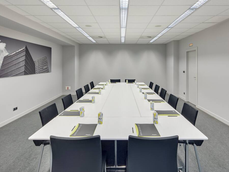 A conference room with a long table, chairs, and a projector screen.