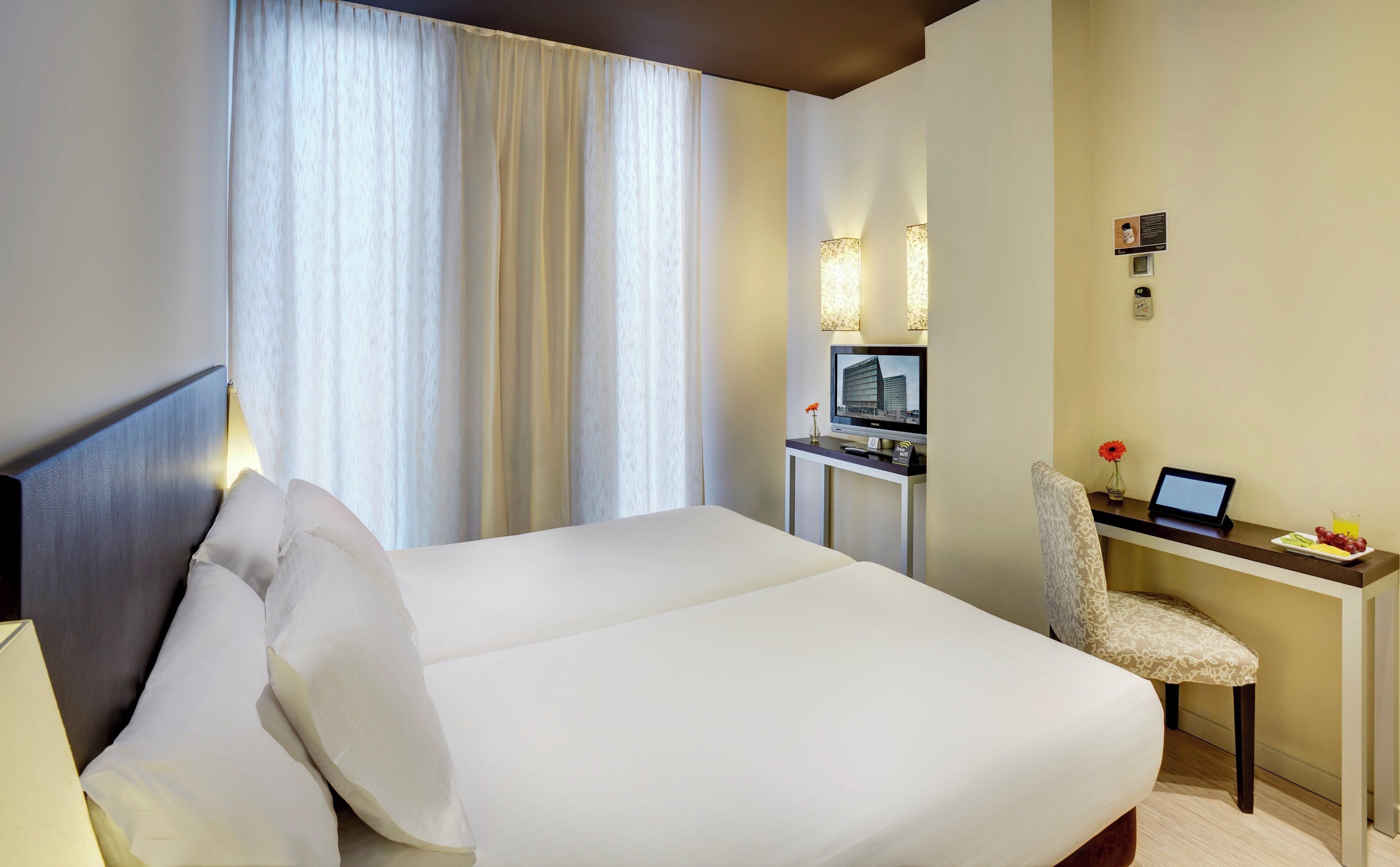 A hotel room with a large bed, a desk with a computer, and a TV.
