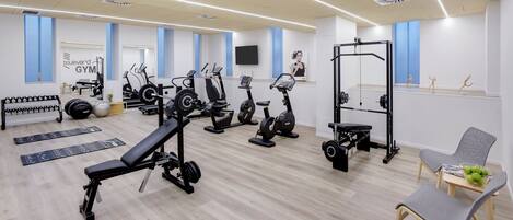 Un gimnasio moderno con diversos equipos de ejercicio, entre ellos cintas de correr, bicicletas estáticas y máquinas de pesas.