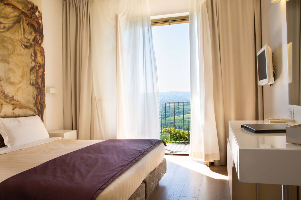 Une chambre d’hôtel avec un lit, un bureau équipé d’un ordinateur et une vue sur l’extérieur.