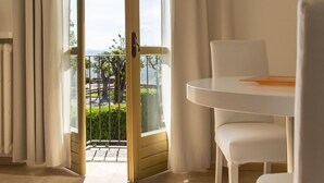 A room with a large glass door leading to a balcony, white furniture, and a view of the outdoors.