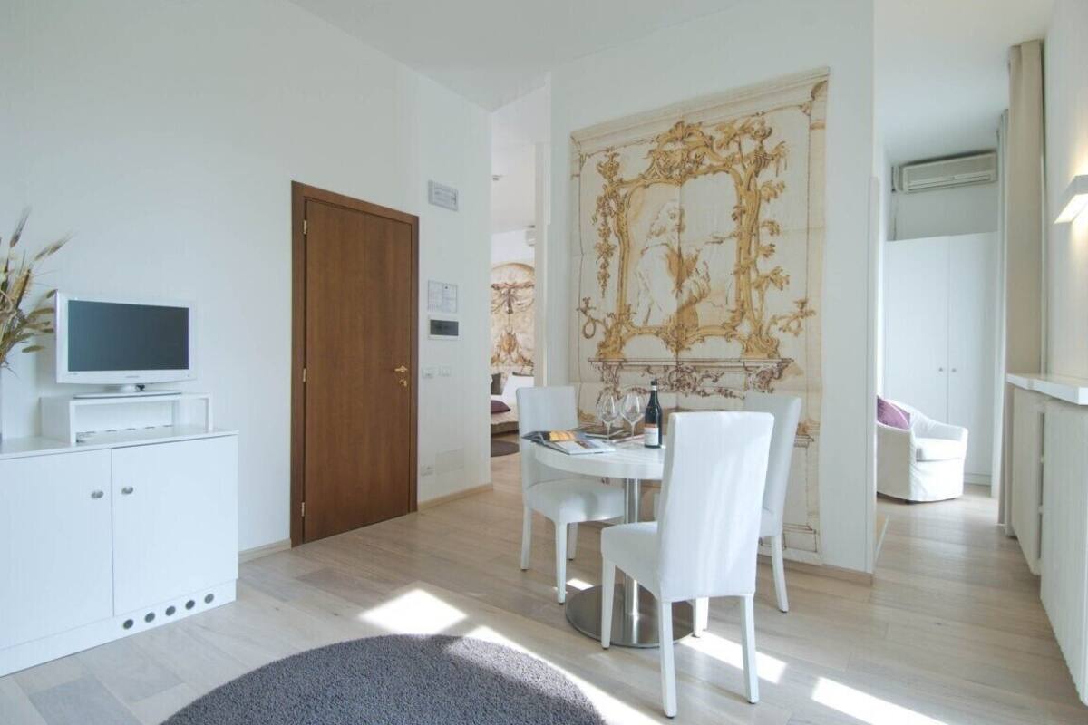 Une pièce moderne comprenant une table à manger, des chaises, un téléviseur posé sur un meuble et un grand élément décoratif mural.