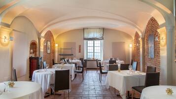 A restaurant with white tablecloths, brick walls, and arched ceilings.