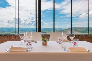 Mesa dispuesta para dos con copas de vino, vasos de agua y cubiertos, con vistas a un paisaje pintoresco.