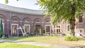 A brick building with arched windows and a covered outdoor seating area. - Eburon Hotel - Different Hotels (Tongeren)
