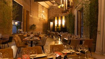 A restaurant with brick walls, wooden tables, and chairs.