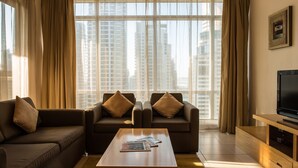A modern living room with two sofas, a coffee table, and a TV stand. - Oaks Liwa Heights Suites (Dubai)