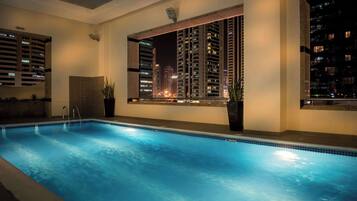 A swimming pool with a view of high-rise buildings at night.