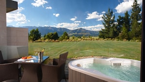 A hot tub with a mountain view, a table with a bottle of champagne, and wicker chairs. - Braemar Lodge And Spa (Hanmer Springs)