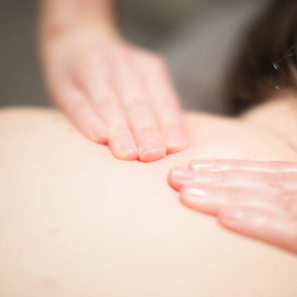 A close-up of hands performing a massage on a person's back.