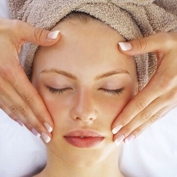 A person with neatly manicured nails resting their head on a pillow.