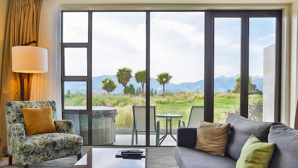 A room with a sofa, armchair, and a table with a lamp. - Braemar Lodge And Spa (Hanmer Springs)