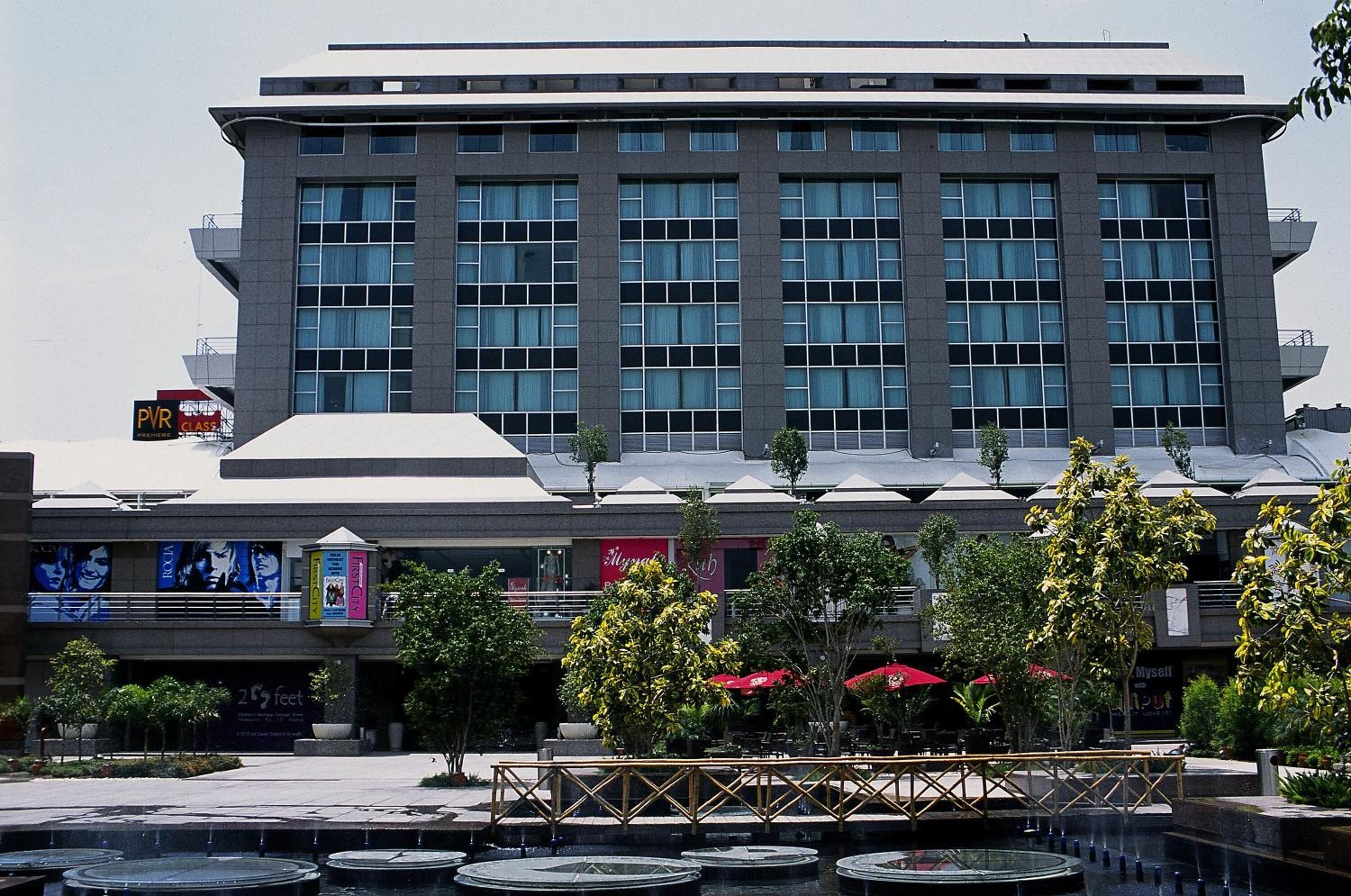 A modern building with a large glass facade, a rooftop terrace, and a central courtyard with a water feature.
