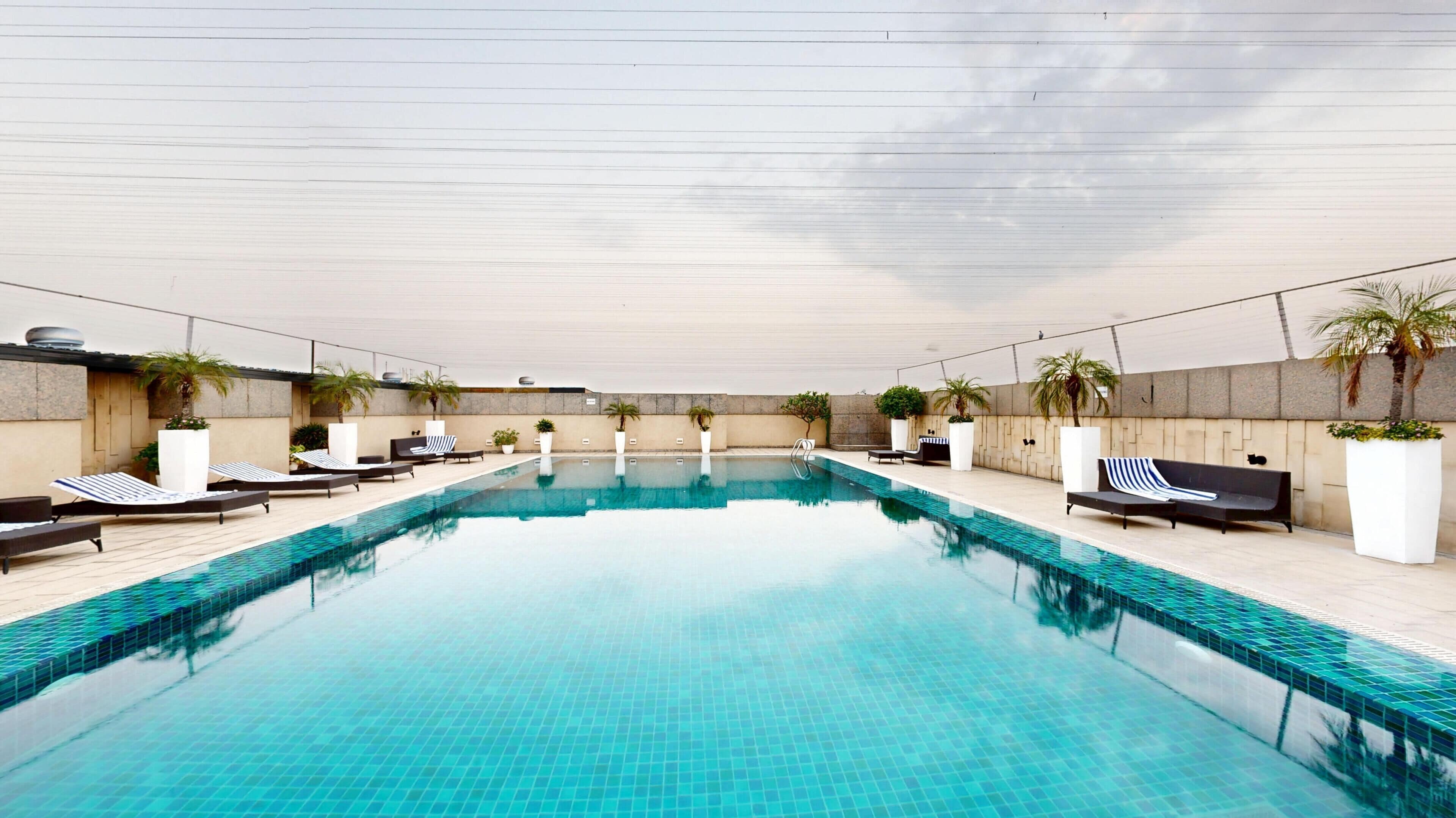 A swimming pool with lounge chairs and potted plants.