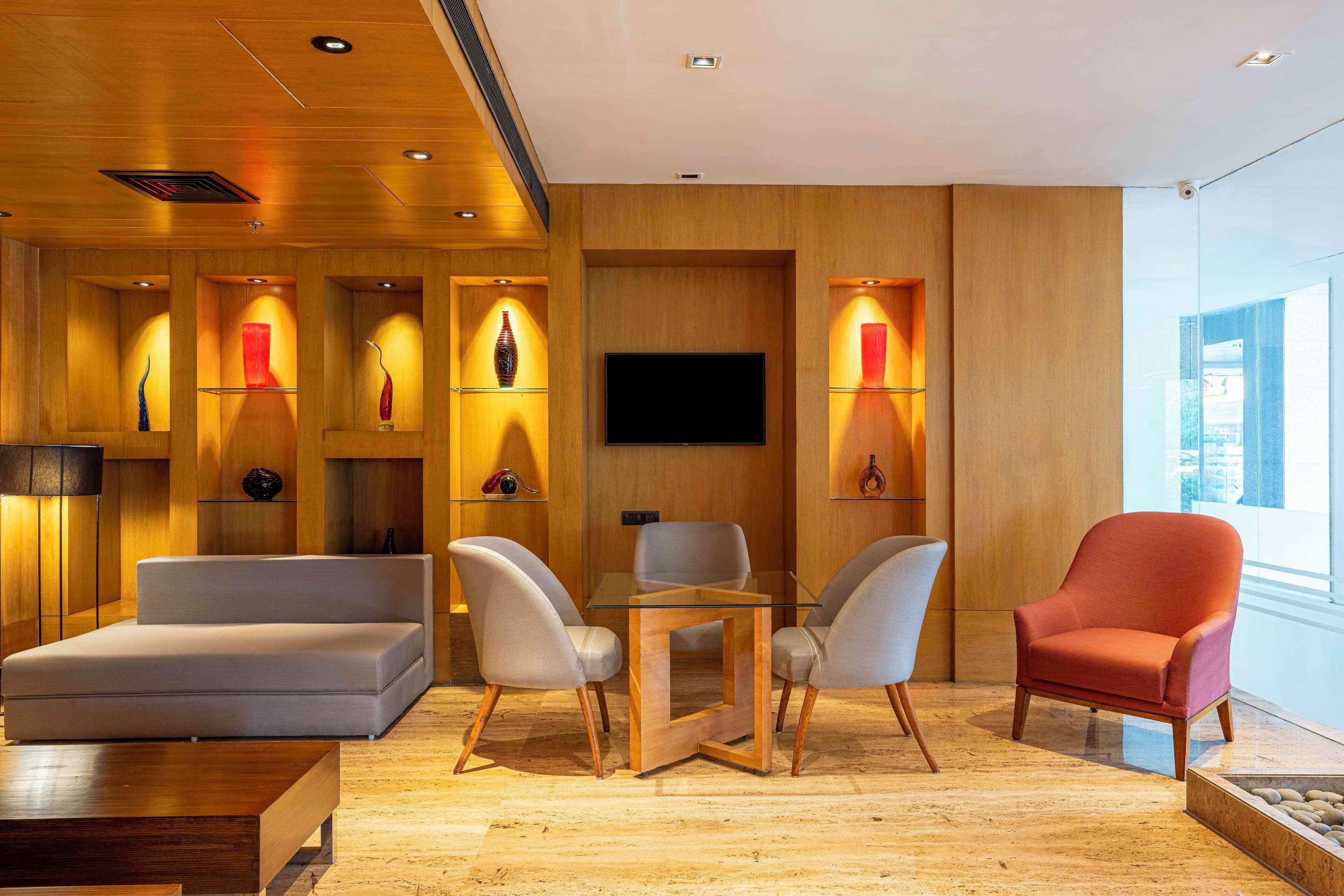 A modern living room with a sofa, two armchairs, a coffee table, and a TV.