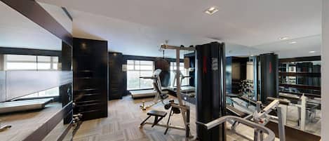 Une salle de sport moderne dotée de divers équipements d’exercice, de grandes fenêtres et d’un aménagement spacieux.