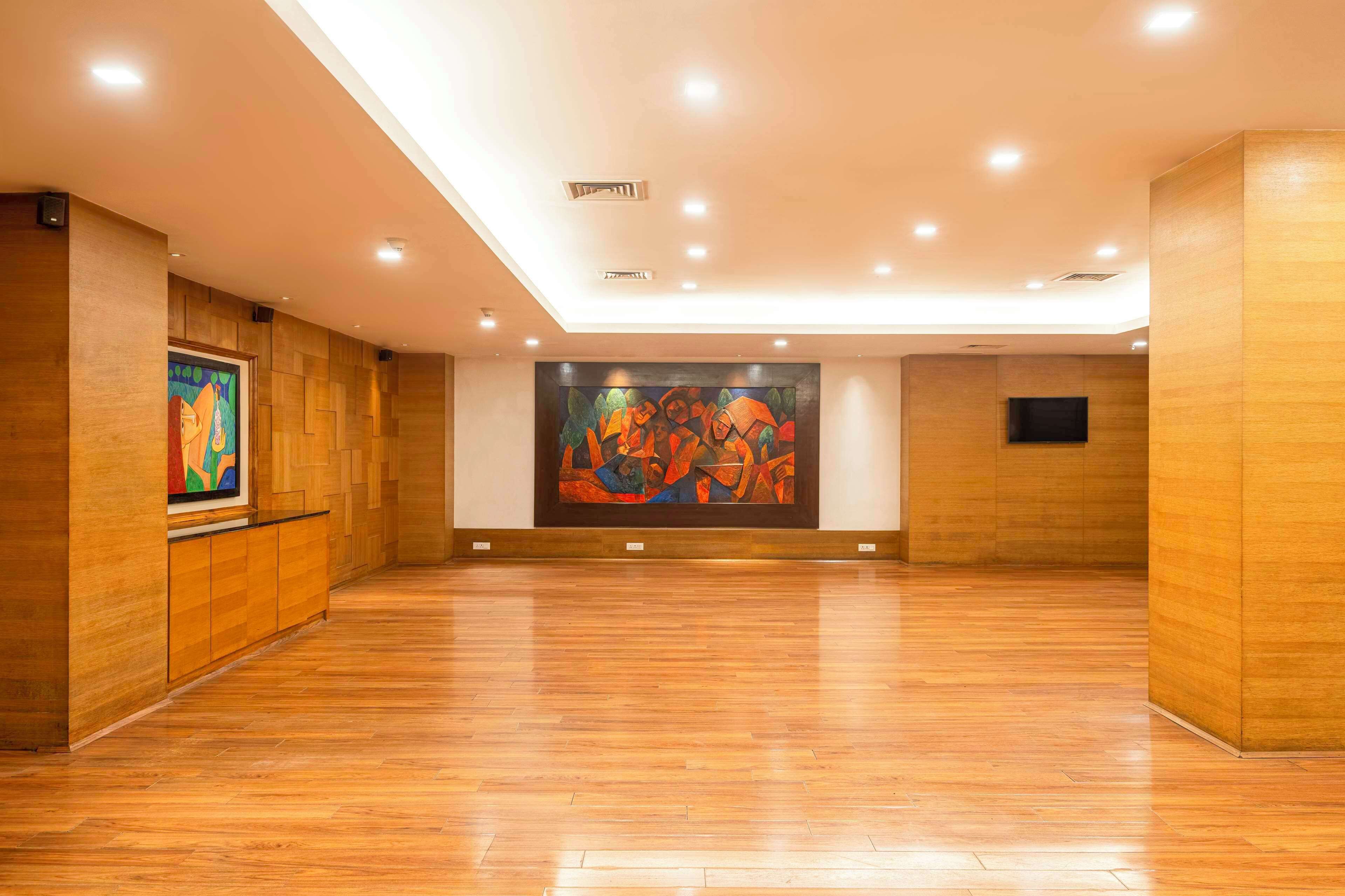 A spacious gallery with wooden floors and walls, featuring two large abstract paintings.