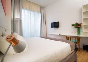 A hotel room with a bed, a desk, a TV, and a vase with flowers. - BA Jardines Palermo (Buenos Aires)