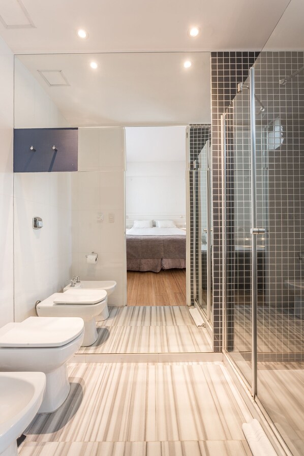 A modern bathroom with a glass shower enclosure, a bidet, and a toilet.