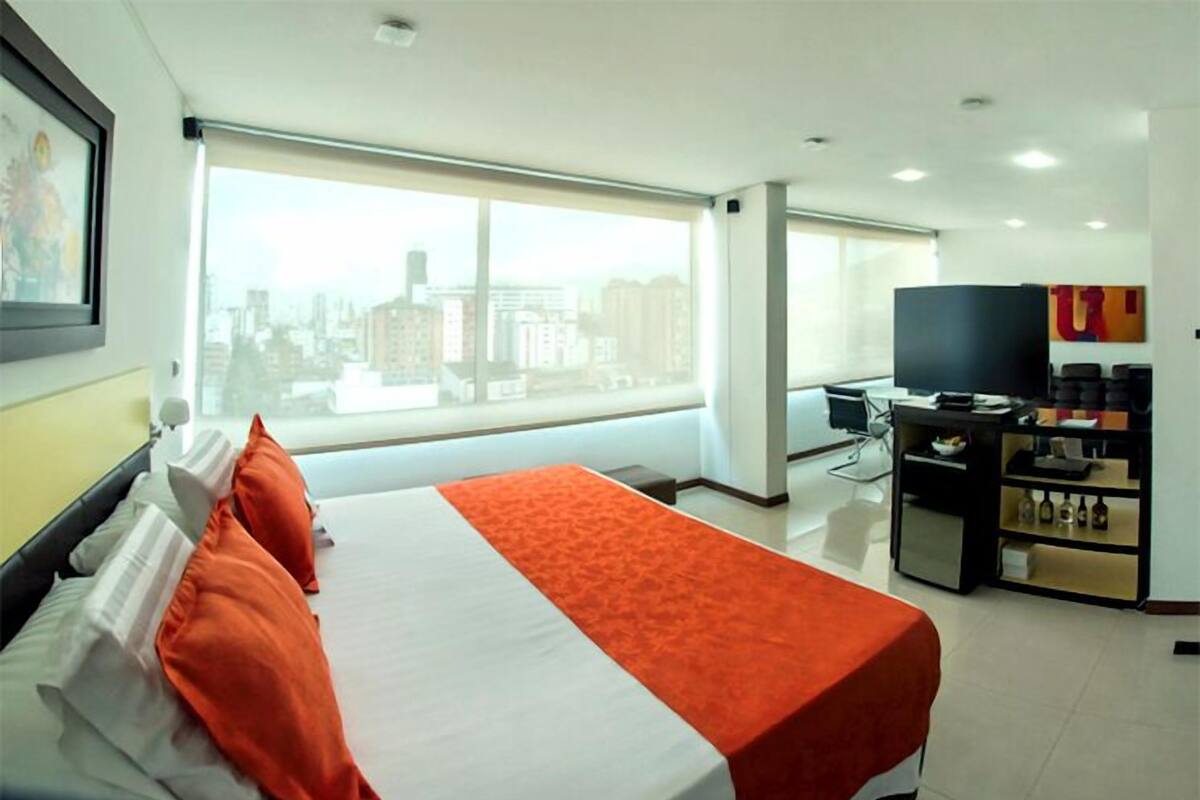 Une chambre d’hôtel avec un grand lit, un bureau, une télévision et une vue sur la ville.